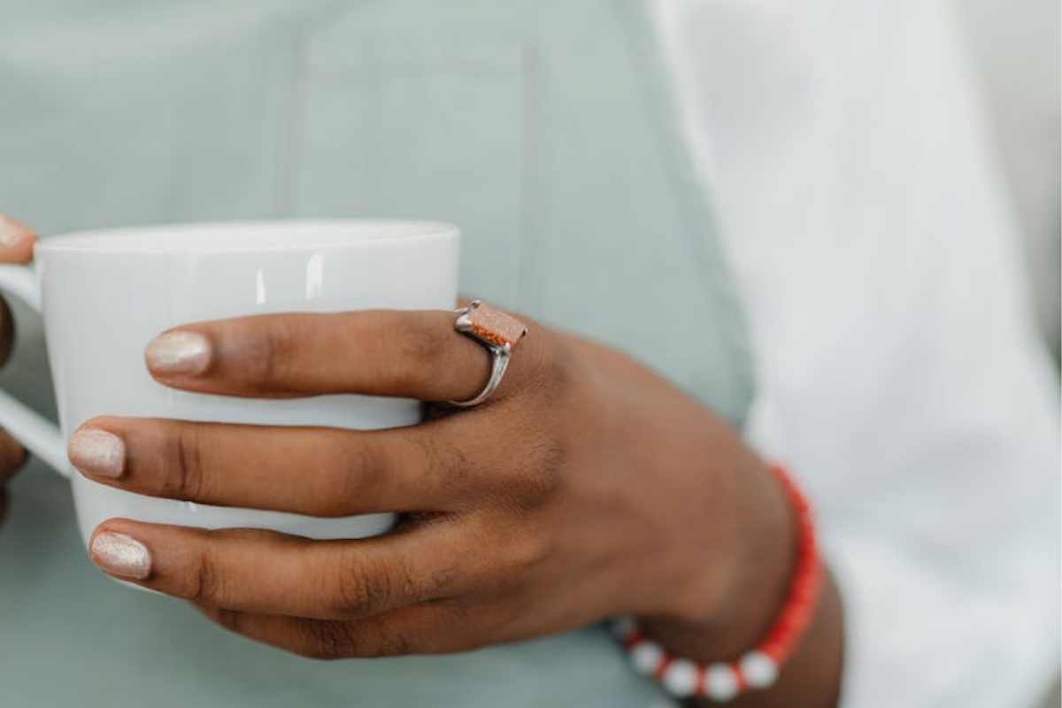 une femme avec une bague au doigt qui boit une boisson chaude